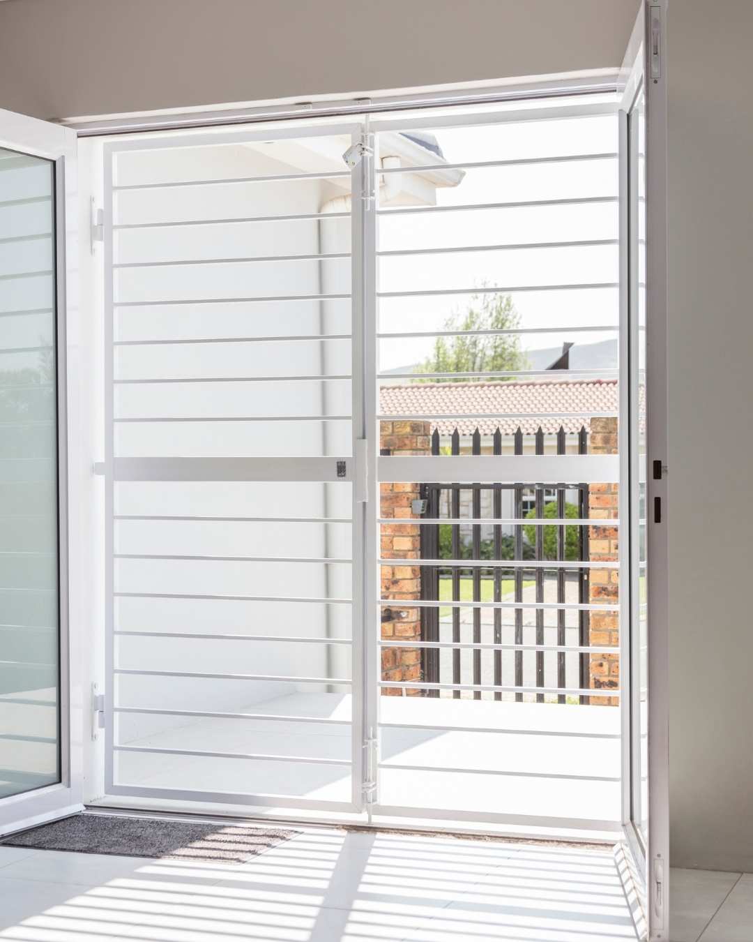 White steel swing gate installed at a sliding door entrance, providing secure and durable access control for residential property.